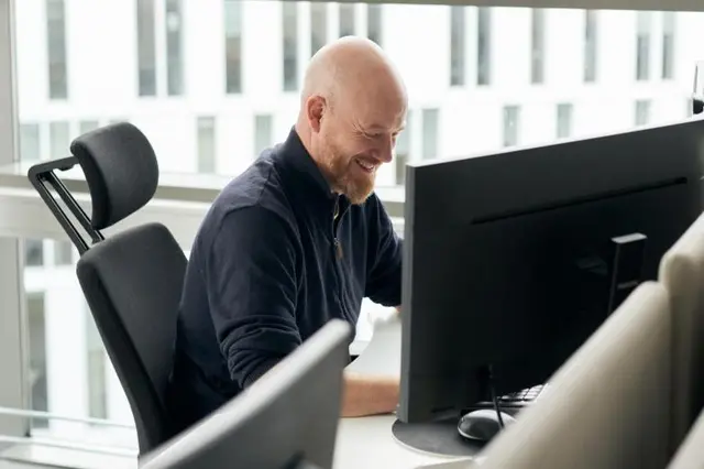Blid mann som sitter foran PC-en